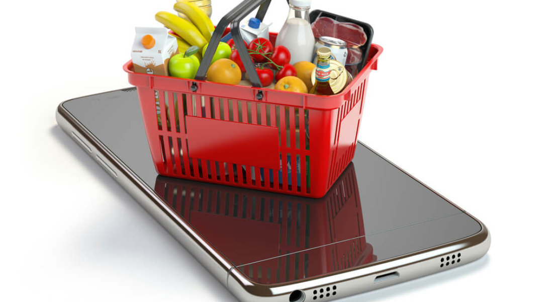 Smartphone and shopping basket with  food and drink. Online grocery supermarket concept.